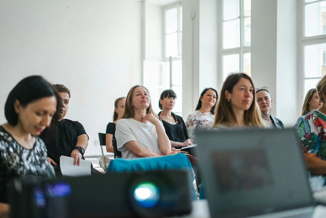 Cả phòng ngồi nghe giảng trong một lớp học kỹ năng, máy chiếu đặt phía trước