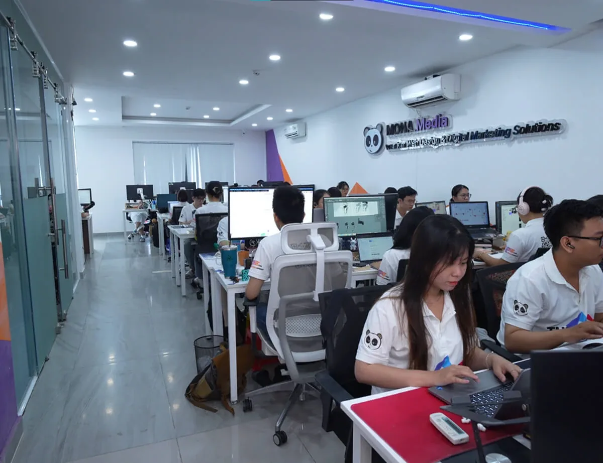 Văn phòng MONA Media, nhân sự mặc đồng phục THE MONA làm việc trên nhiều màn hình